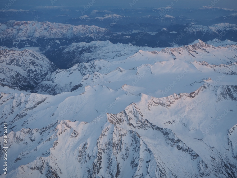 Flying over the Adamello Presanella Alps during winter season. Landscape at the glaciers. Aerial view from the airplane window