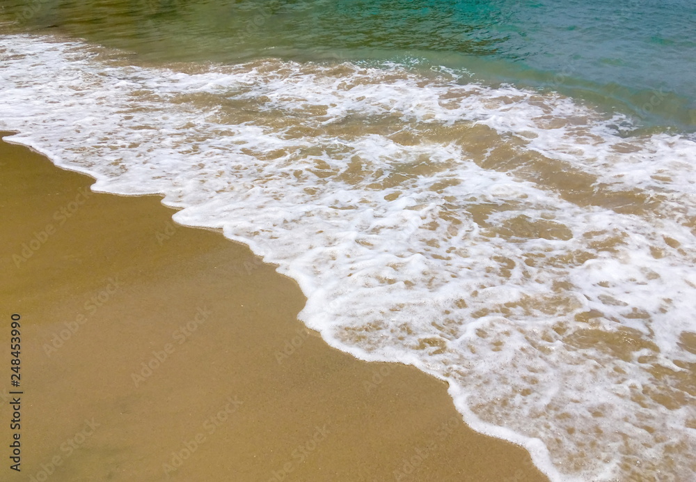 White foam of blue sea on sandy beach background White foam of blue sea on sandy beach background