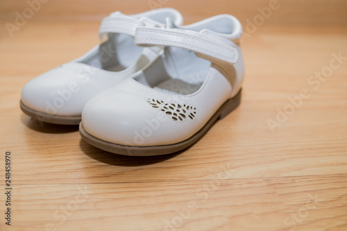 Color female shoes. Kids footwear isolated on wooden background.white leather baby shoes, slippers.White festive, elegant shoes for a preschooler.Copy space