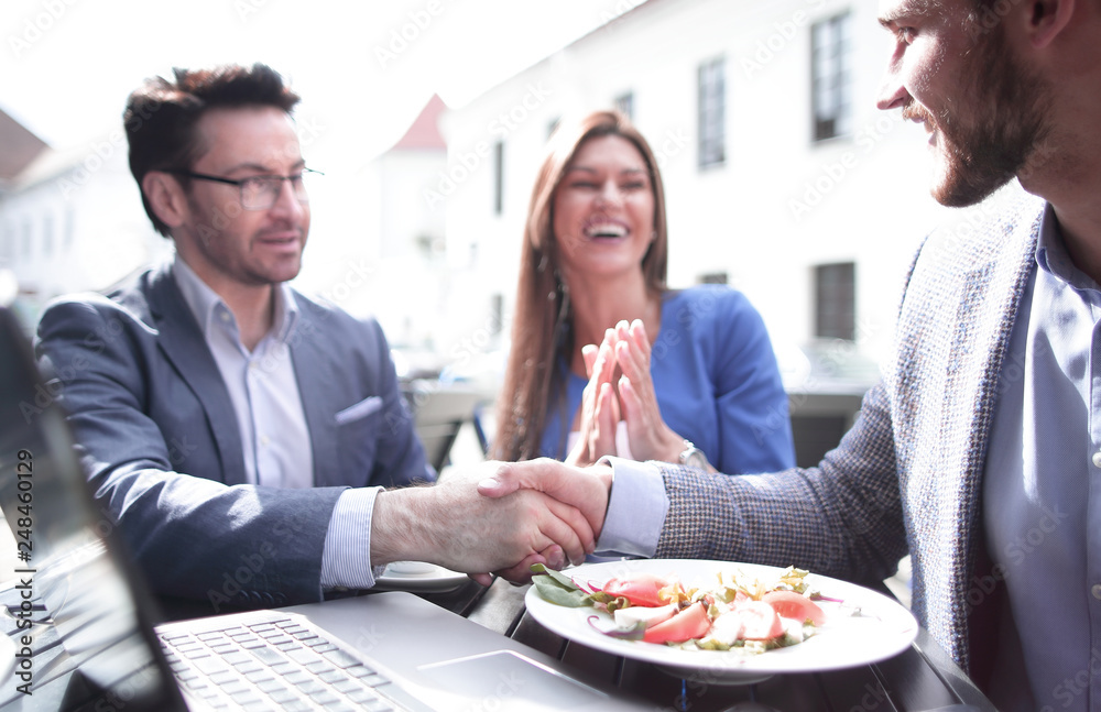 colleagues greeting each other with a handshake in the cafe colleagues greeting each other with a handshake in the cafe