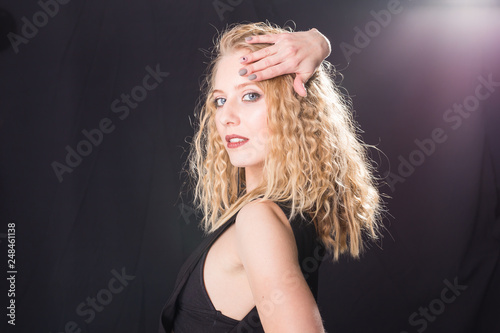 Portrait of sensual blond woman with curly hair over light grey background with copy space