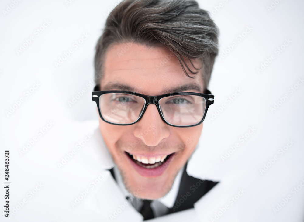 young businessman breaking through a white paper wall