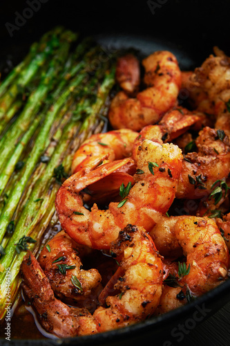 fried langoustines with asparagus decorated with lemon slices. roasted king prawns tiger shrimps with green garnish