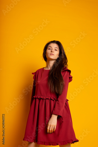 Attractive, Slim, Beautiful, Brunette Girl Wearing Red Silk Fabric Dress Fly And Wave In The Wind Posing in Studio on Yellow background. Spring colletcion concept © Максим Галінский