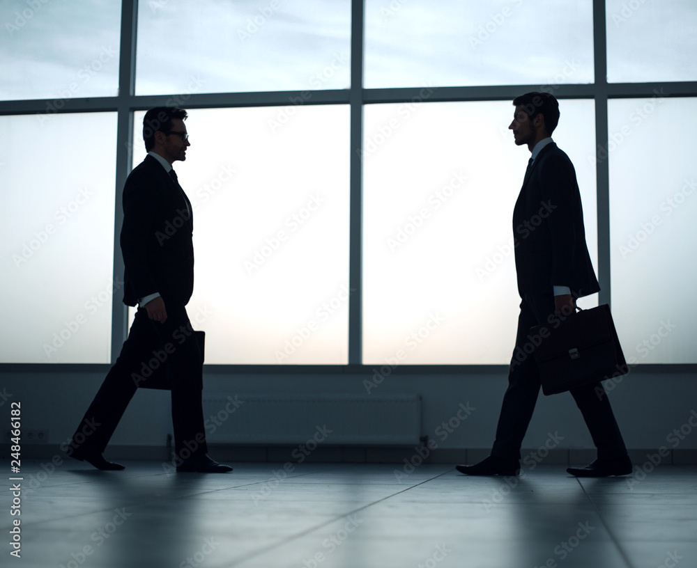 two businessmen are walking towards each other two businessmen are walking towards each other