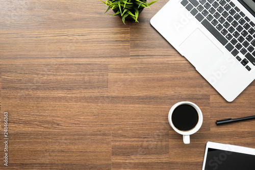 Wood office desk table with laptop, a cup of coffee and supplies. Top view with copy space, flat lay.