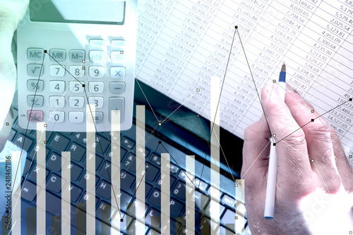 Pointing at spreadsheet on laptop with calculator and bar chart