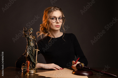 Pretty young woman in a glasses and in a black dress sitting and wrighting importaint document, notary woman ratify notary documents photo