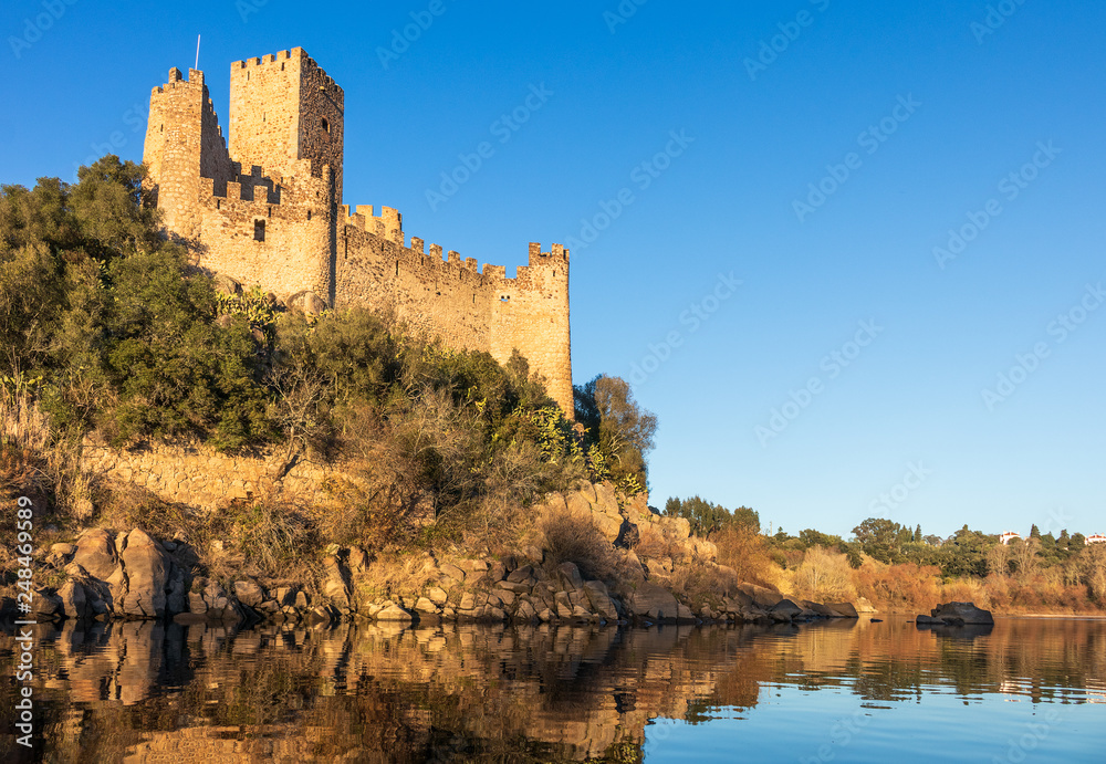 Almourol, Portugal - January 12, 2019: View of the Almourol castle from the Tagus river, lit by the late afternoon sun with blue sky.