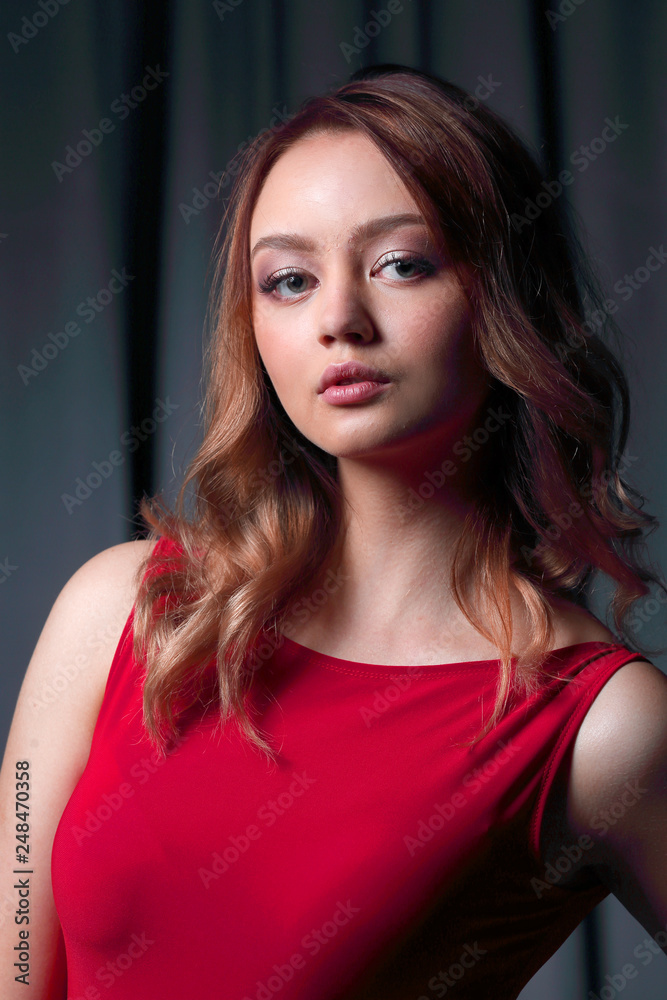 Charming brunette in a red dress posing on a black background.
