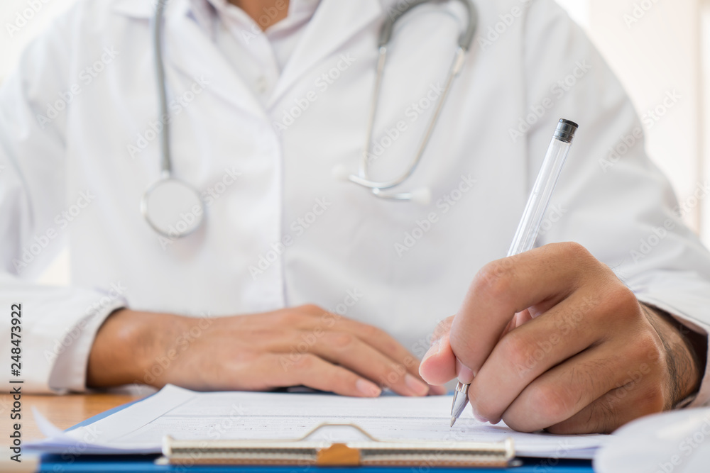 Healthcare medical Expenses concept, Hands Doctor's writing and working on prescription clipboard with record information paper folders on desk in hospital or clinic. Selective focus Healthcare medical Expenses concept, Hands Doctor's writing and working on prescription clipboard with record information paper folders on desk in hospital or clinic. Selective focus