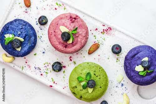 homemade raw vegan colorful cakes with matcha, acai and butterfky pea tea, fresh berries, mint, nuts photo