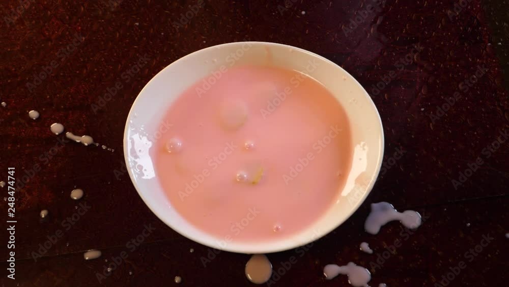 Sliced banana falls into strawberry yogurt in slow motion Sliced banana falls into strawberry yogurt in slow motion