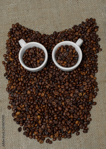 Owl made from coffee beans. Whole bean coffee. Coffee beans in the shape of an owl. Coffee cup on coffee beans. Coffee beans on burlap © Євген Малюга