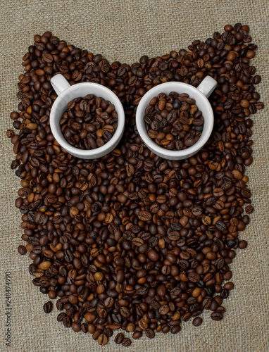 Owl made from coffee beans. Whole bean coffee. Coffee beans in the shape of an owl. Coffee cup on coffee beans. Coffee beans on burlap