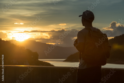 Image of sunrise with a silhouette of a tourist man in natural surrounding