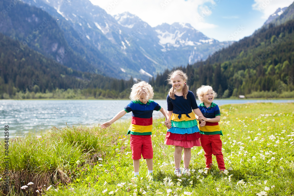 Children hiking in flower field at mountain lake Children hiking in flower field at mountain lake