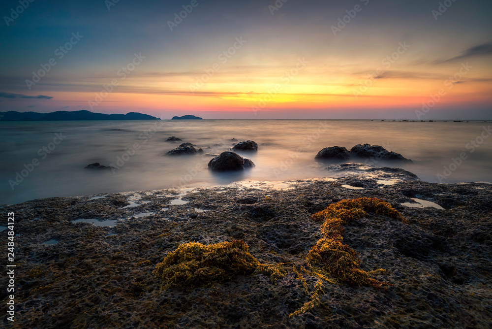 Rocks rock along the beach sand in the twilight. 