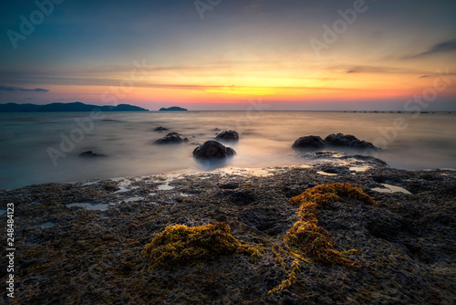 Rocks rock along the beach sand in the twilight. 
