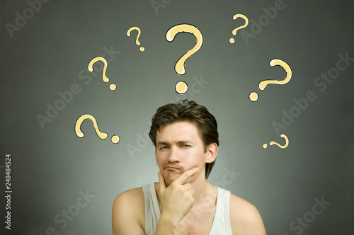 Man thinks and question marks overhead. Stock photo.