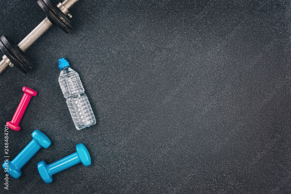 Fitness or bodybuilding concept background. Product photograph of old iron dumbbells on black grey, conrete floor in the gym. Photograph taken from above, top view with lots of copy space Fitness or bodybuilding concept background. Product photograph of old iron dumbbells on black grey, conrete floor in the gym. Photograph taken from above, top view with lots of copy space