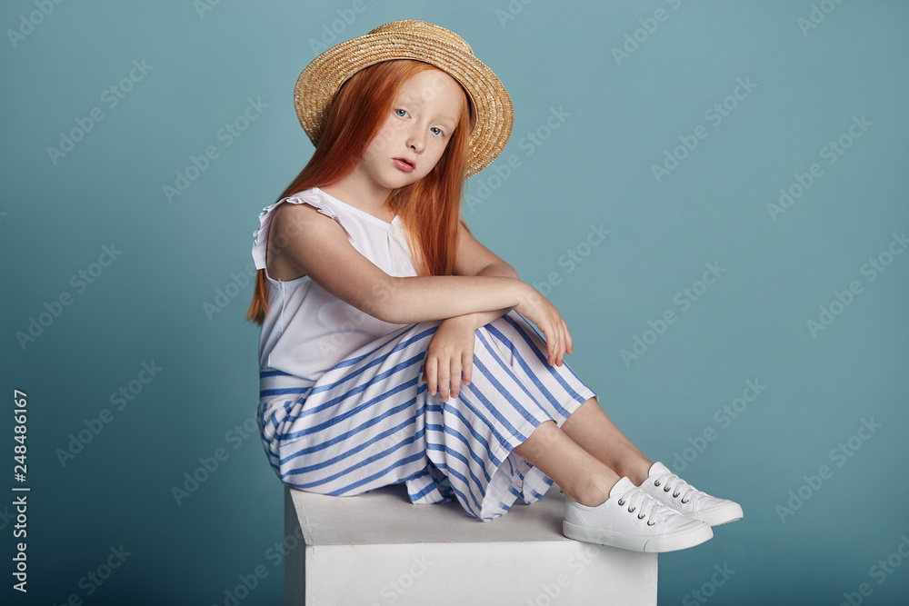 Norwegian girl with bright red hair in a straw hat. Beautiful redhead baby  girl with long