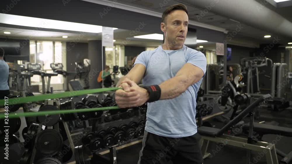 Man doing side-to-side chops exercise with elastic band at the gym. Man doing side-to-side chops exercise with elastic band at the gym.
