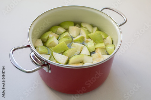Cooking apple juice. Slices of green apples in a saucepan with water.