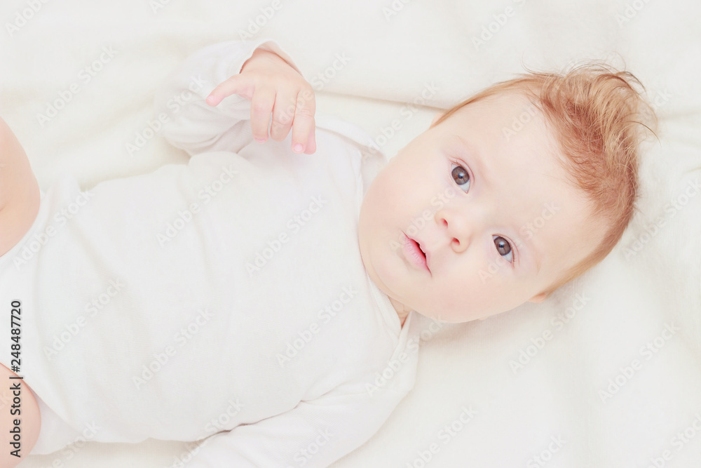 Happy child on the white blanket, blurred background Happy child on the white blanket, blurred background