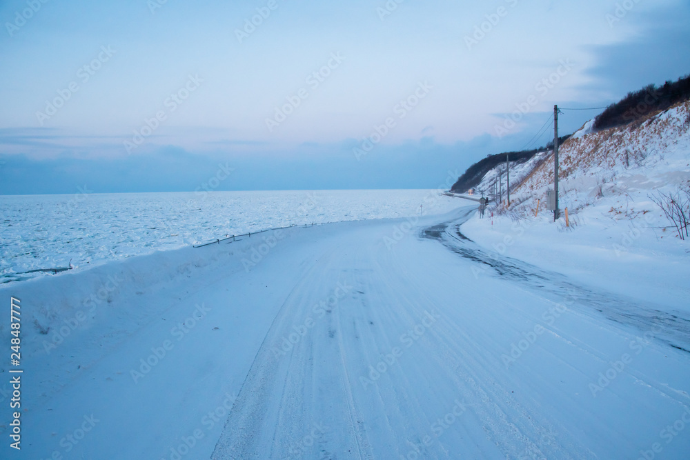 冬の流氷に覆われたオホーツク海沿いの道（北海道・斜里町）