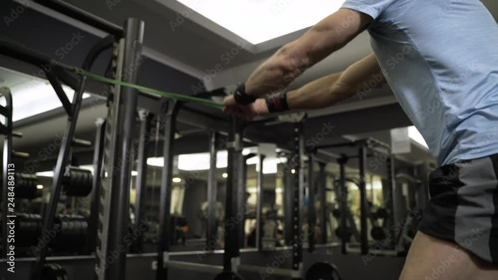Close up image of man doing exercise with elastic band at the gym.