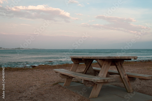 Wooden public pic nic table overlooking the south african ocean  almos astunset  pink light