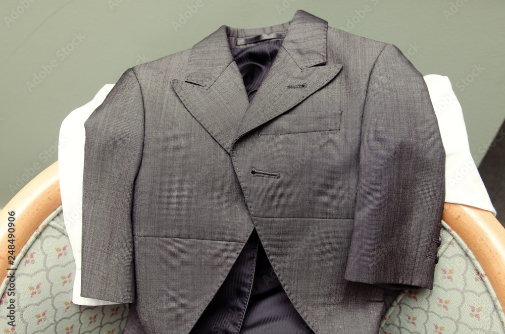 A fashionable childs  grey wedding suit, suit tops and trousers, laid out ready to get changed into. getting ready at a wedding celebration.