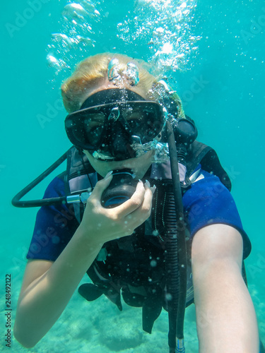 Young caucasian  woman dressed in diving equipment swimming underwater in ionian sea .Greece , Corfu scuba diving in vacation   Women   making selfie underwater