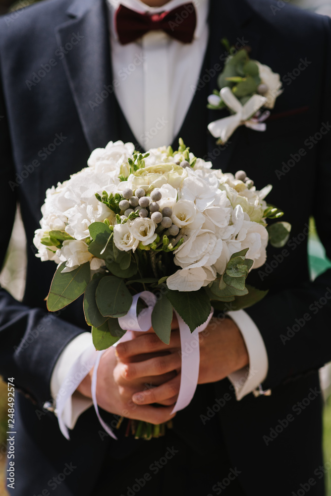 A groom holding a beautiful wedding bouquet closeup A groom holding a beautiful wedding bouquet closeup