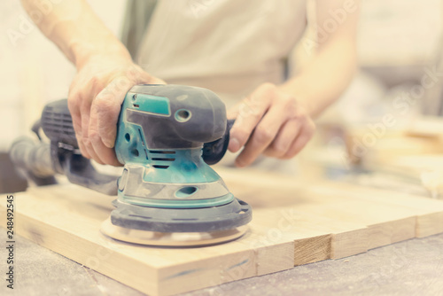 Worker grinds the wood of angular grinding machine