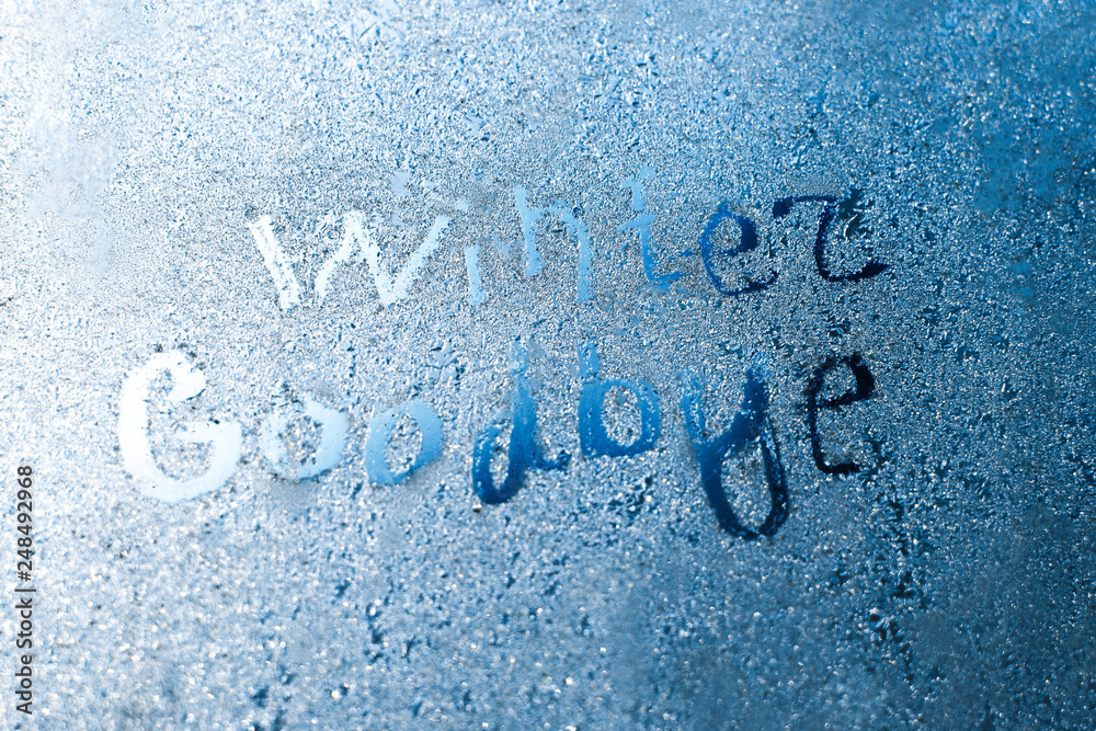 The inscription: goodbye, winter. On a frozen winter window in frosty patterns The inscription: goodbye, winter. On a frozen winter window in frosty patterns