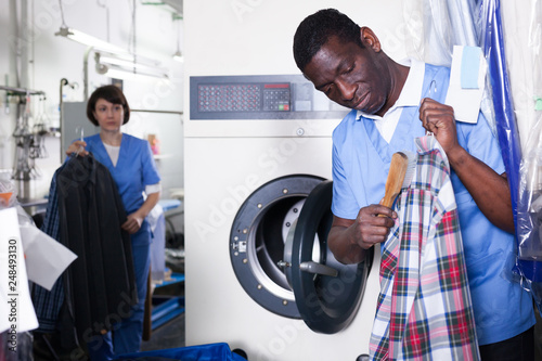 Man dry cleaning clothes in laundry photo