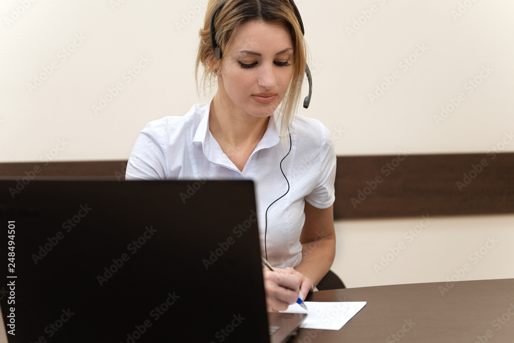 Beautiful call center worker in headphones are working at modern office. Beautiful call center worker in headphones are working at modern office.