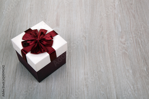 white gift box with a bow on a gray wooden background © mizar_21984