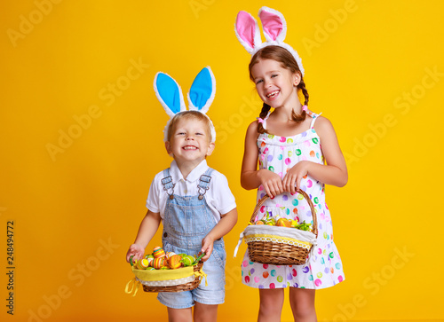 funny happy child boy with easter eggs and bunny ears on yellow