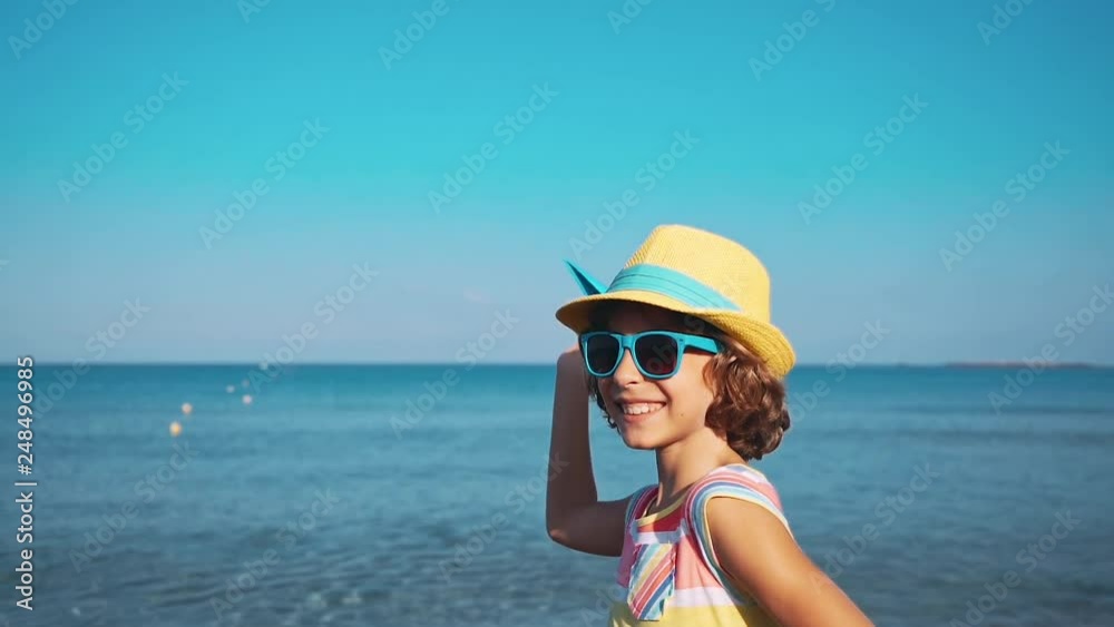 Happy child playing with paper airplane against sea and sky background. Kid pilot having fun outdoor. Summer vacation and travel concept. Freedom and imagination Happy child playing with paper airplane against sea and sky background. Kid pilot having fun outdoor. Summer vacation and travel concept. Freedom and imagination