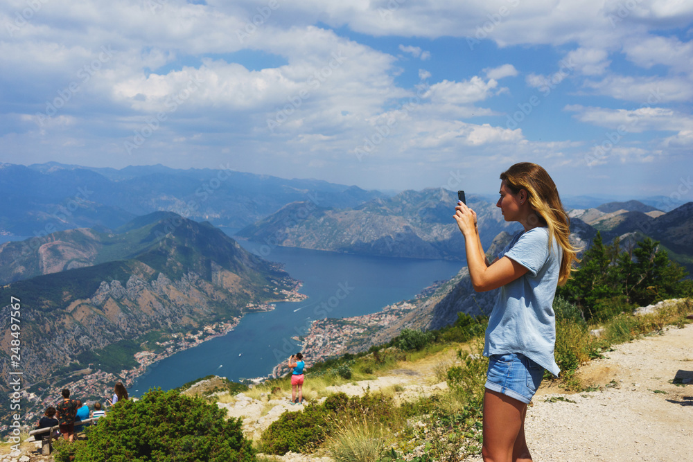 Traveler smartphone, landscape photography. Attractive girl takes story on smartphone while traveling mountains in Montenegro.