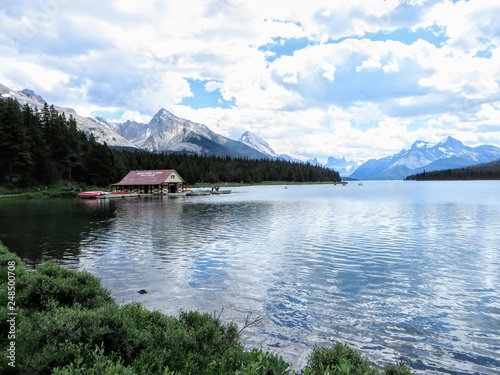 Maligne lake in Jasper national park, with calm and still waters and a handful of rowboats for tourists to rent on a quiet July summer day.