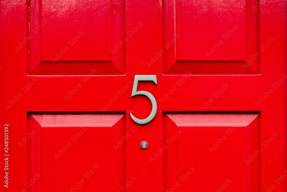 House door number five as a bronze number on a red wooden house door House door number five as a bronze number on a red wooden house door