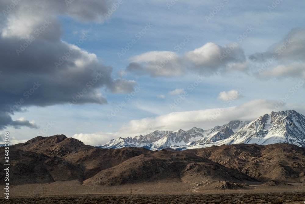 snowy mountains brown desert hills clouds sky Eastern Sierras of California winter landscape