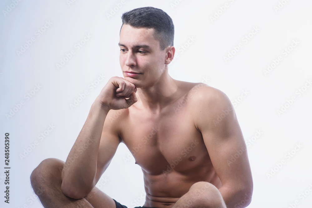Fototapeta premium Beautiful young European athletic with bare torso, nice abs and muscles on white and gray background