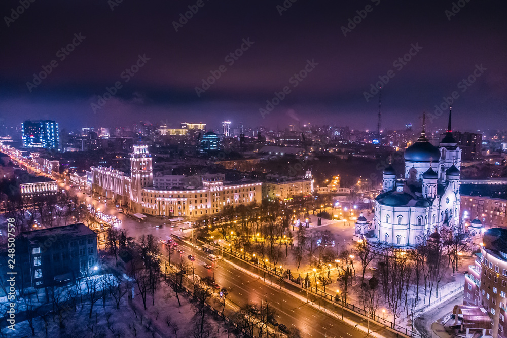 Arial view of Voronezh Main South-Eastern Railway Building tower in night, symbol of Voronezh and evening cityscape with rads, parks and traffic, drone shot
