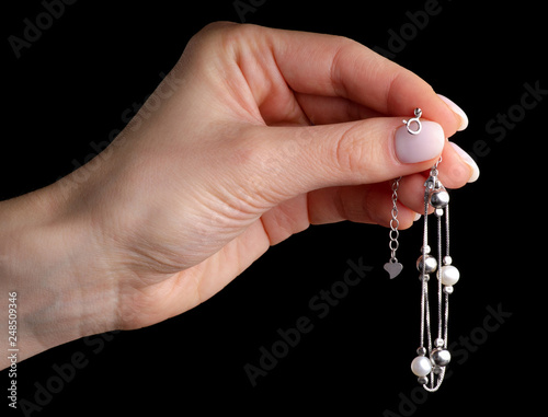 Jewelry silver bracelet with pearls on the hand on a black background. Isolation