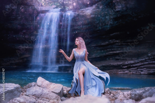 Fototapeta Naklejka Na Ścianę i Meble -  attractive sexy water fairy with sad face, fantastic nymph near lake in Georgia, Martvili Canyon nature. tender girl with long blue flying dress, pink hair. creative art processing, creative colors